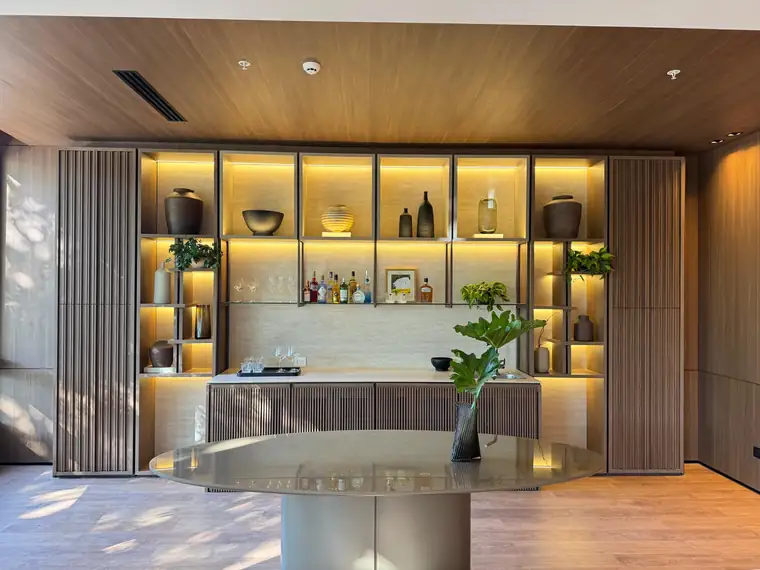 Bar de madera y travertino con nichos iluminados y piezas de cerámica artesanal
