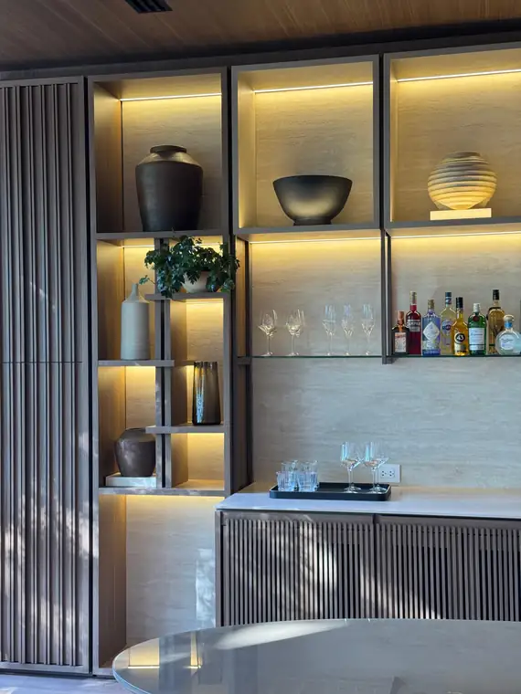 Detalle de estantería iluminada con jarrón, cuenco y bowl de cerámica hecha a mano